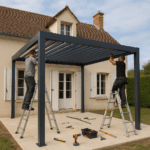 Deux personnes montent sur des échelles pour assembler une pergola en métal sur un patio à l'extérieur d'une maison beige. Des outils et du matériel sont éparpillés sur le sol à proximité.